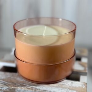 Soy and coconut wax blend candle in an orange round glass container with lid