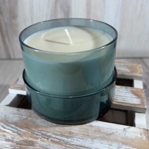Soy and coconut wax blend candle in a teal round glass container with lid.